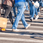 Lots of people from the waist down walking in a cross walk.