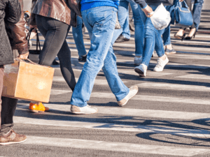 Lots of people from the waist down walking in a cross walk.