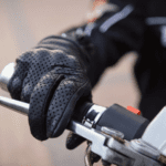 A gloved hand holding the throttle of a motorcycle.
