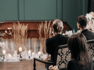 people sitting in front of a wooden casket.