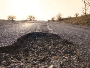 A close up of a pot hole in the middle of an asphalt road.